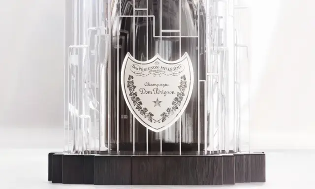 Dom Pérignon Vintage 2012 in einer modernen, transparenten Hülle mit dunklem Holzsockel.