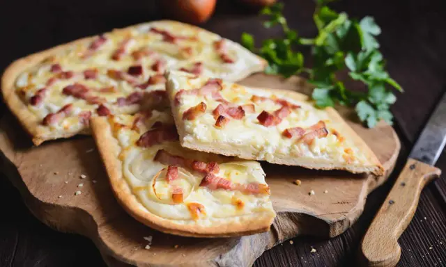 Flammekueche, une spécialité alsacienne d'origine, garnie de lardons et d'oignons sur une pâte fine.