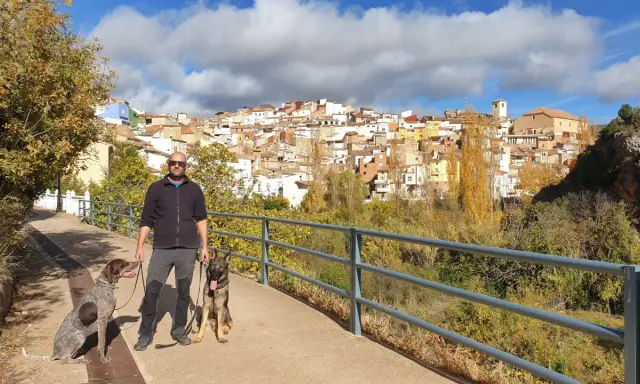 Hombre paseando con dos perros por la ruta de las esculturas de Bogarra, con el pueblo al fondo.