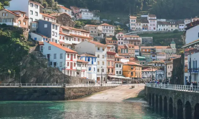 Casas de colores se aferran a la ladera en uno de los pueblos con encanto en Asturias, con el mar turquesa al frente.
