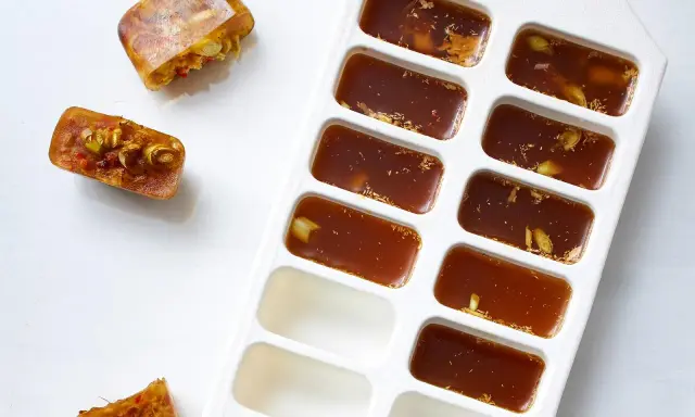 Eiswürfelbehälter mit gefrorener Brühe und Gewürzen. So kann man einfach Suppe einfrieren und später verwenden.