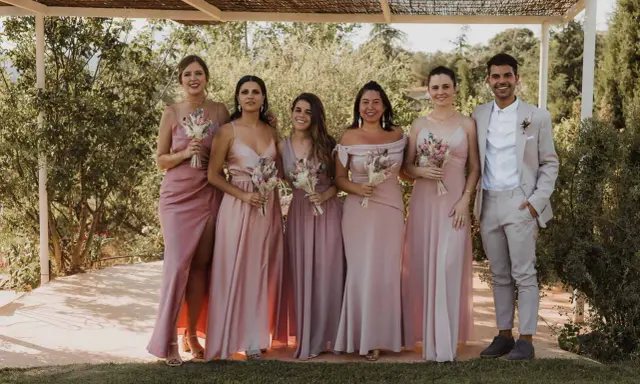 Grupo de damas de honor y el novio posando para una foto en una boda informal campo.