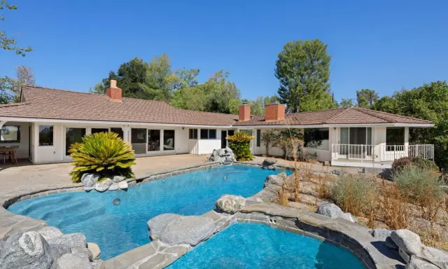 La piscina e il giardino di una casa che ricorda lo stile del **Kim Kardashian house**, con un'architettura moderna e un'area esterna rilassante.