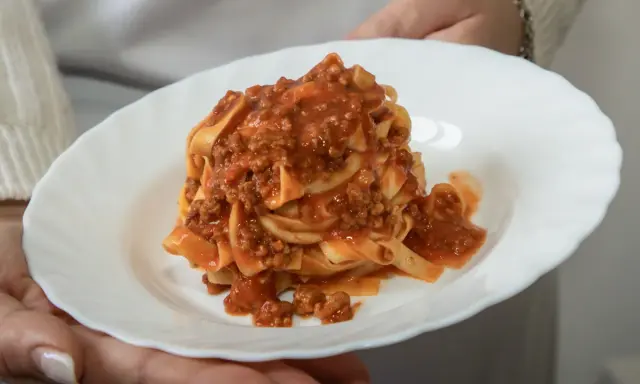 Un piatto di tagliatelle al ragù, un classico della cucina italiana, servito su un piatto bianco.