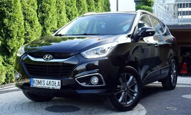 Czarny Hyundai ix35 2.0 benzyna + LPG, lśniący na podjeździe przed zielonym żywopłotem.
