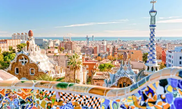 Kolorowe mozaiki i bajkowe budowle w Parku Güell z widokiem na Barcelonę.