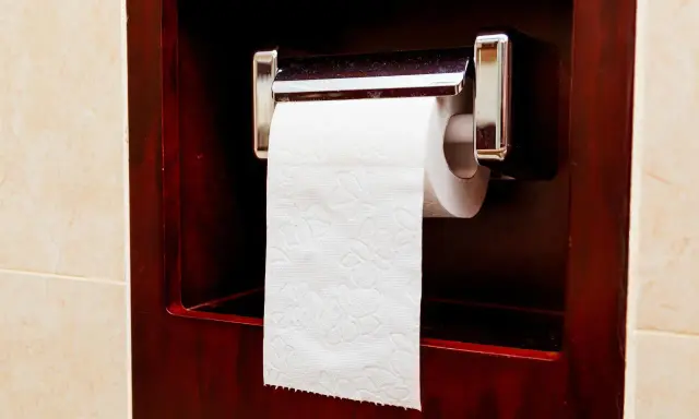 Uchwyt na papier toaletowy zamontowany jest na wygodnej wysokości, w ciemnej, drewnianej wnęce.