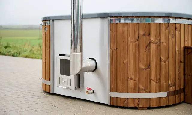 En badtunna hybrid med träpanel och metall, redo för ett avkopplande bad utomhus.