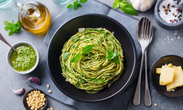 Pyszny obiad bez mięsa: spaghetti z pesto, świeżą bazylią, orzeszkami pinii i parmezanem.