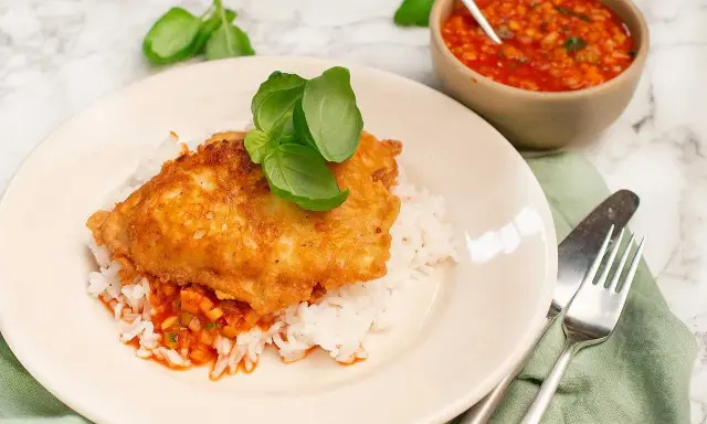 Krispig kyckling piccata serverad på ris med en smakrik tomatsås och färsk basilika. En härlig måltid!