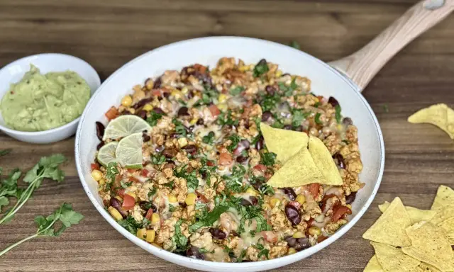 Pyszny kurczak po meksykańsku z fasolą, kukurydzą i serem, podany z guacamole i nachos.