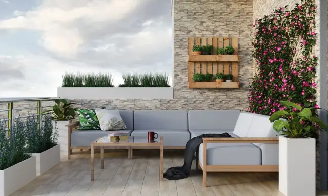 Przytulny balkon w bloku z szarą sofą, drewnianym stolikiem i kwitnącym bluszczem. Idealne miejsce na relaks po myciu balkonu w bloku.