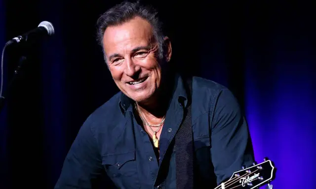 Bruce Springsteen ler glatt på scenen i Sverige, med gitarr och mikrofon redo för en oförglömlig kväll.