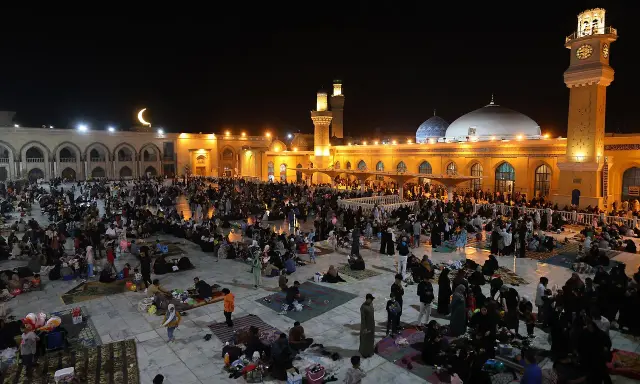 Menschen versammeln sich nachts auf einem Platz vor einer Moschee, um die Qadr Nacht zu begehen.