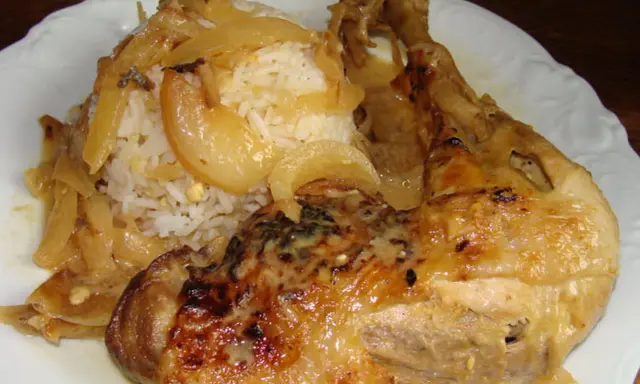 Un plat de poulet yassa savoureux avec du riz blanc et des oignons caramélisés.