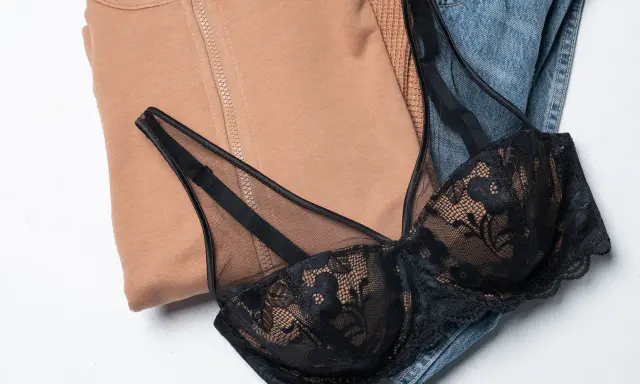Un reggiseno di pizzo nero adagiato su jeans e felpa color cammello. Pensando a ogni quanto si cambia il reggiseno, questo è un capo che merita cura.