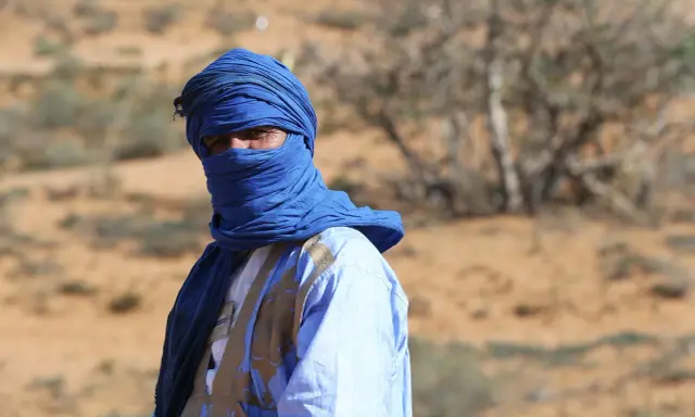 Ein Mann in traditioneller blauer Kleidung und Turban blickt aus der Wüste. Sind Marokkaner Araber? Ja, viele Marokkaner sind Araber.