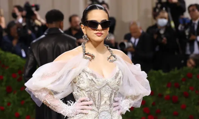 Rosalía deslumbrante en la Met Gala, con un vestido blanco adornado y gafas de sol vanguardistas.