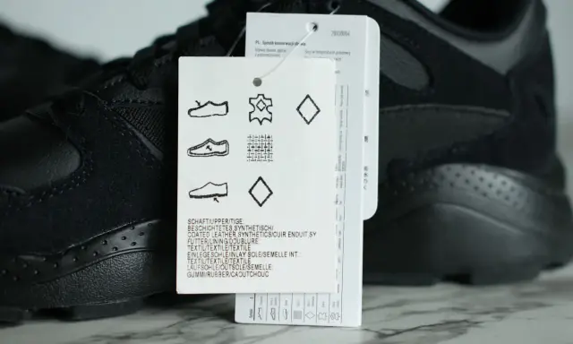 Czarna cholewka w adidasach, wykonana z połączenia skóry i materiałów syntetycznych, z widoczną metką z symbolami pielęgnacji.