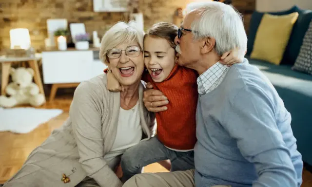 Abuelos riendo y abrazando a su nieta. Un momento tierno que demuestra la alegría de los padres que dejan a sus hijos con los abuelos.