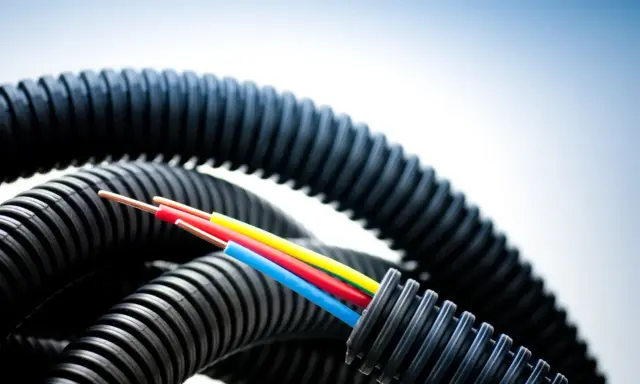 Trois câbles colorés sortent d'une gaine ondulée noire. La question est : combien de cable dans une gaine ?