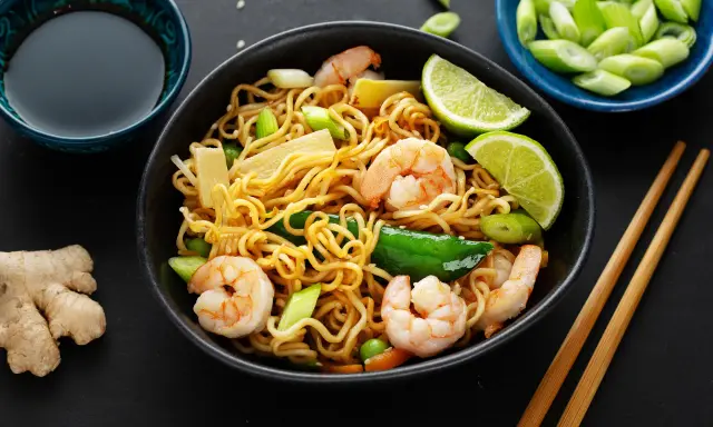 Makaron chow mein z krewetkami, warzywami i limonką, podany z sosem sojowym i imbirem.