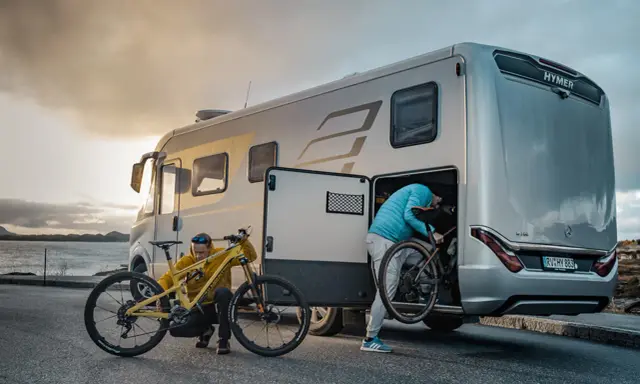 Zwei Personen laden Mountainbikes in einen Hymer Wohnwagen. Perfekt für Abenteuer mit dem e-bike wohnwagen.