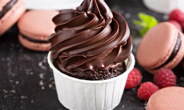 Gourmandise chocolatée : un cupcake avec ganache montée, macarons et framboises. Idéal pour la conservation ganache montée frigo.