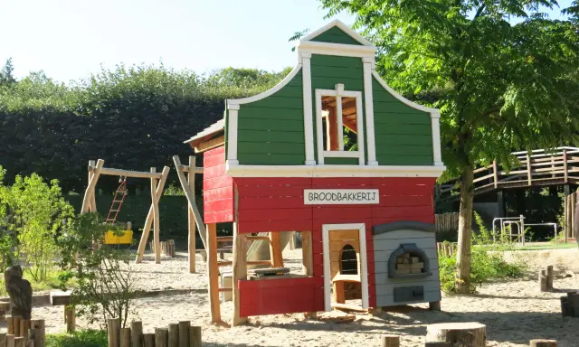 Parque infantil en Holanda con casita de panadería, columpios y tobogán. Ideal para que los niños jueguen y se diviertan.