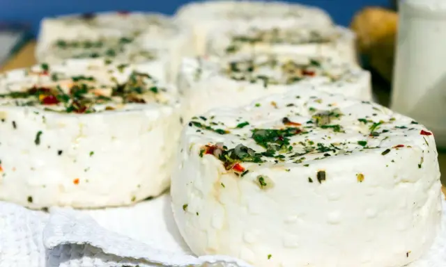 Kilka okrągłych serów labneh z ziołami i przyprawami na białej serwetce.