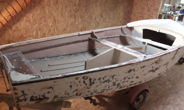 Un dériveur Caravelle polyester en cours de restauration, sur sa remorque. La coque est décapée, prête pour une nouvelle peinture.