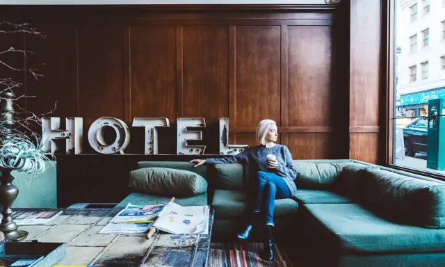 Kobieta siedzi na kanapie w hotelu, zastanawiając się, ile zarabia technik hotelarstwa.