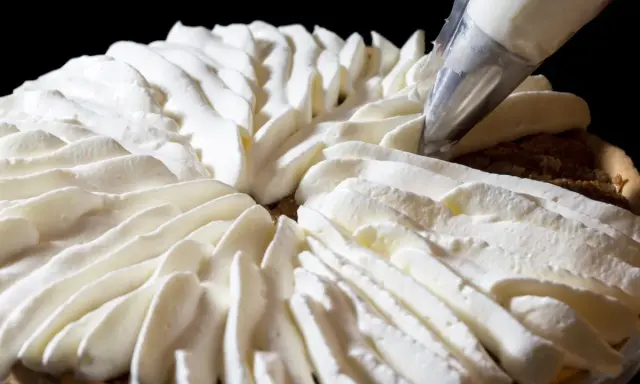 Garniture d'une tarte avec une poche à douille, évoquant la recette crémeux vanille Michalak.