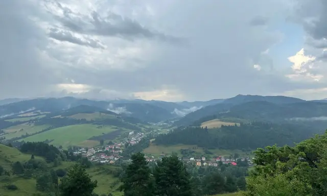 Widok na dolinę z wioską i górami w tle, chmury nad przełęczą pod Tokarnią.