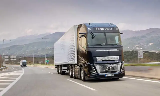 Camión Volvo FH Aero 780 negro con remolque blanco avanza por una carretera montañosa.