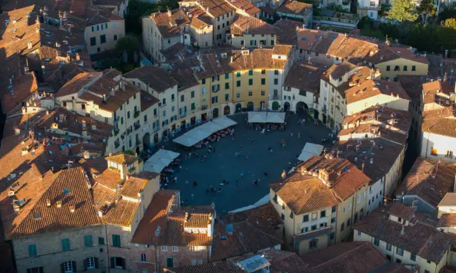 Vista aerea di Piazza dell'Anfiteatro a Lucca, perfetta per un weekend indimenticabile tra tetti rossi e vita cittadina.