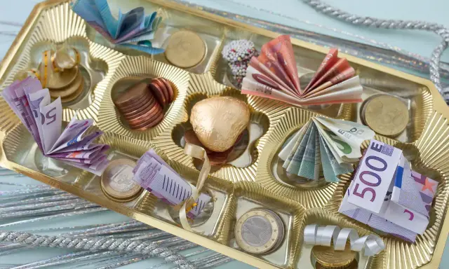 Pudełko czekoladek ze złotym sercem i banknotami euro. Pomysł, jak śmiesznie zapakować prezent na 18.