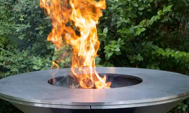 Un moderno braciere da giardino, con fiamme vivaci che danzano al centro, crea un'atmosfera accogliente.