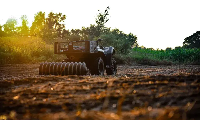 ATV with a roller attachment, ready for field work. This is one of many tractor attachments that can help prepare the soil.