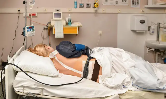 Pacjentka w łóżku szpitalnym, podłączona do aparatury. Znieczulenie w kręgosłup skutki uboczne mogą być różne, ale tu skupiamy się na monitorowaniu.