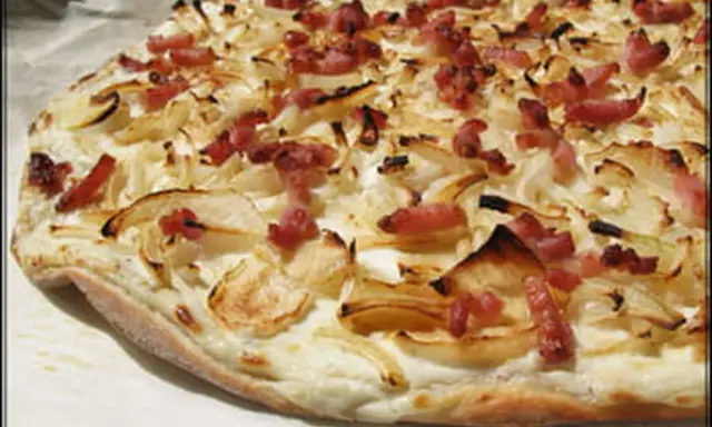 Flammekueche croustillante, garnie d'oignons et de lardons. Une recette facile pour un plat savoureux.