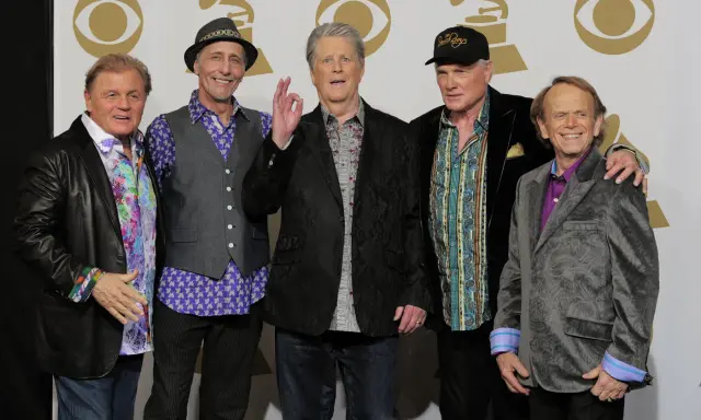 Fem leende medlemmar av The Beach Boys poserar för ett foto.