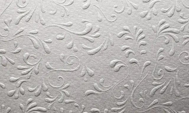 Srebrzyste, wytłaczane wzory roślinne na papierze, przypominające eleganckie uszlachetnienia druku.