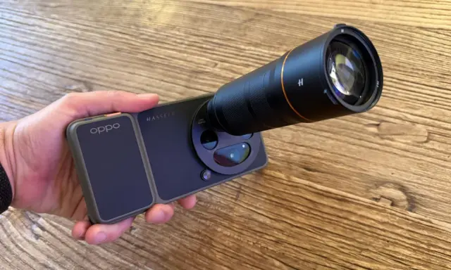 Mano sujetando un teléfono **cámara Oppo** con un gran lente acoplado, listo para capturar imágenes detalladas.