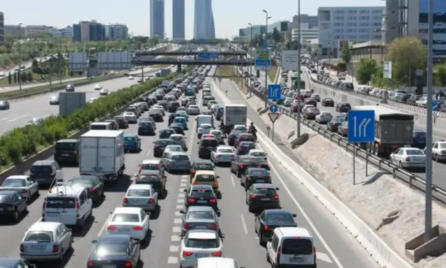 Congestión vehicular en una autopista, reflejo de la movilidad urbana. Coches y camiones detenidos en múltiples carriles bajo un cielo despejado.
