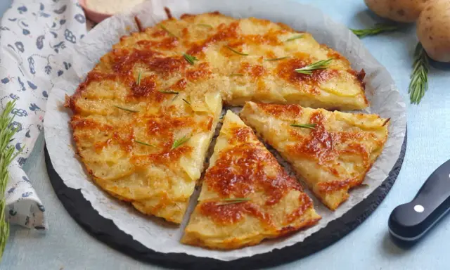 Una deliziosa torta di patate dorata e croccante, guarnita con rosmarino fresco, pronta per essere gustata.
