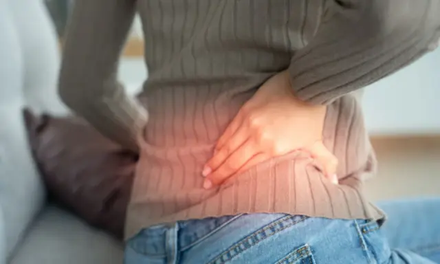 Kobieta z bólem w boku, wskazującym na możliwe przyczyny pomniejszonej nerki.