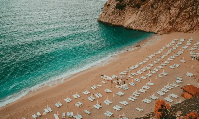 Piękna plaża z rzędami leżaków i turkusową wodą. Idealne miejsce, gdzie do Turcji na wakacje.