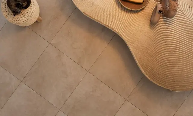 Kot śpi na pufie, obok falistego stolika z bananami i wazonami. Podłoga z gres lappato czyszczenie jest nieskazitelna.