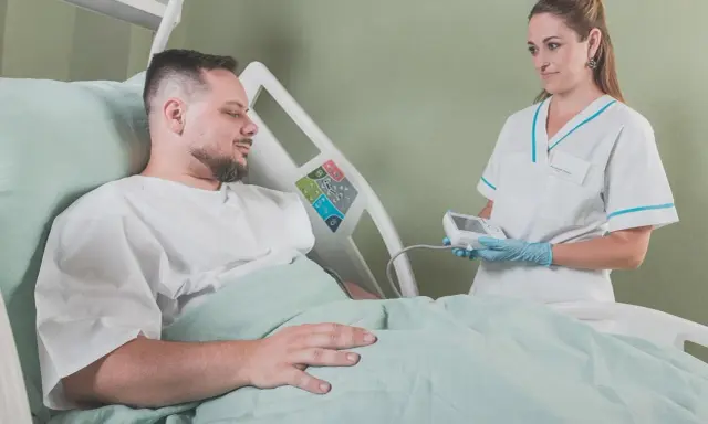 Pielęgniarka bada pacjenta w szpitalu. Walka z rakiem i nowotworem wymaga wsparcia medycznego.